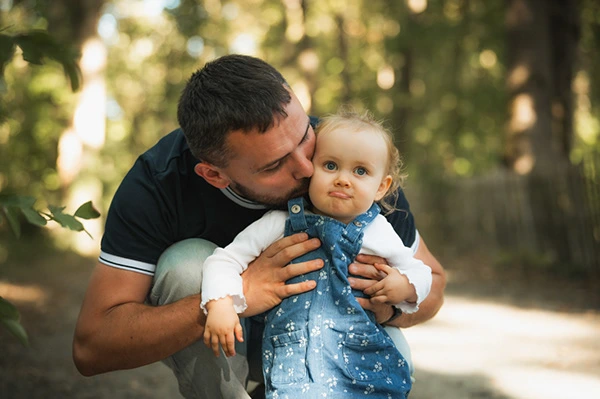 Un père embrasse son enfant lors d’une séance en famille en extérieur — Paul Dehée